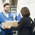 Kurir ekspedisi menyerahkan paket kepada pelanggan di depan rumah, menggambarkan layanan pengiriman paket terdekat