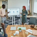 Tim penjualan yang beragam berdiskusi strategi dalam rapat bisnis dengan presentasi visual